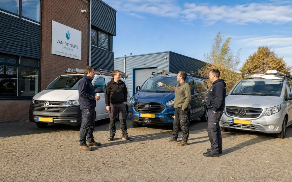 Vier monteurs bespreken 's ochtends de dag bij hun bussen voor het bedrijfspand